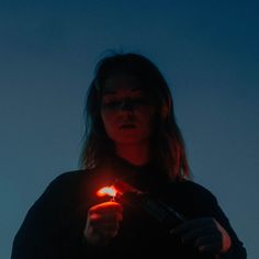 a woman holding a lit lighter in her right hand and looking down at the camera