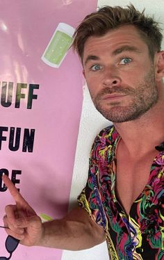 a man standing in front of a pink sign with the words stuff stuff on it