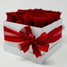 a white box filled with red roses on top of a table