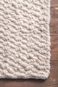 a white rug on top of a wooden floor next to a wood flooring board