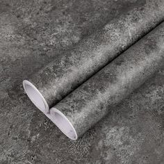 a roll of grey fabric on top of a cement floor with a white round object in the middle