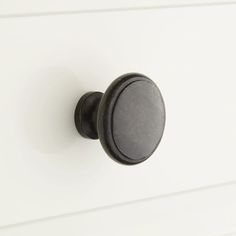 a black knob on a white cabinet door