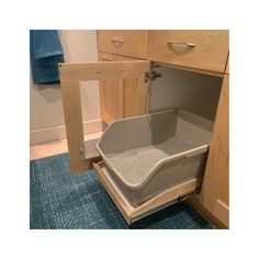 a cat litter box in the corner of a kitchen cabinet with blue rugs on the floor