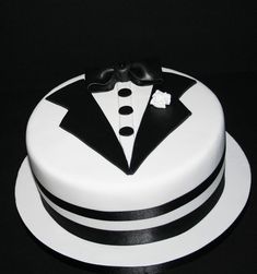 a white cake topped with a black and white tuxedo on top of a table