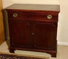 a wooden cabinet with two doors on the front and one door open to reveal a rug