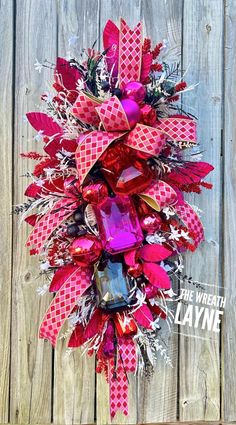 a pink and red wreath with candy on it next to a wooden fence ornament