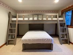 a bunk bed in a room with two ladders on the wall and a white bedspread