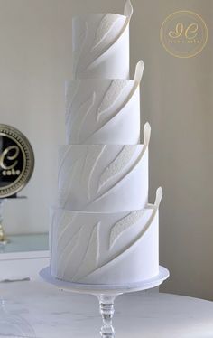 a three tiered white wedding cake sitting on top of a table next to a clock