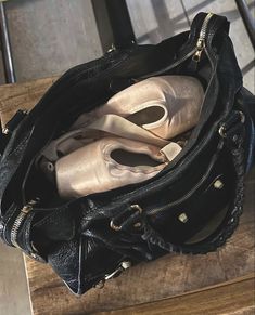 a black purse sitting on top of a wooden table next to a pair of shoes