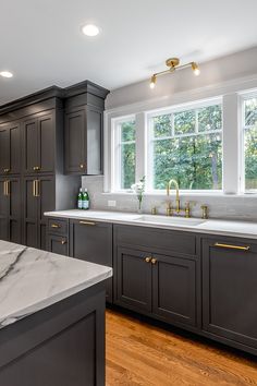 a large kitchen with marble counter tops and dark cabinets, along with hardwood floorsing