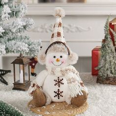 a snowman sitting in front of a christmas tree