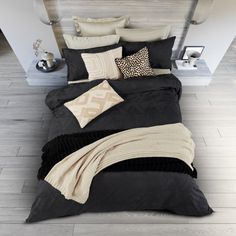 a bed with black and beige comforters, pillows and blankets on top of it