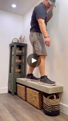 a man standing on top of a bench next to a shelf with baskets in front of him