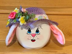 a white ceramic bowl with a bunny face painted on the side and flowers sticking out of it