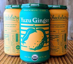 three cans of yuzu ginger beer sitting on top of a wooden table next to each other