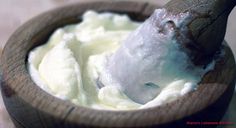 a wooden bowl filled with whipped cream and an animal sticking out of it's mouth