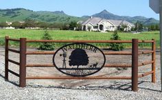 a sign that is on the side of a wooden fence in front of a house