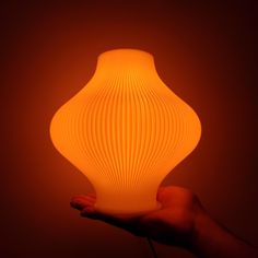 a hand holding an orange light bulb in the dark