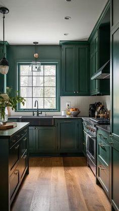 a kitchen with dark green cabinets and wood flooring, along with an island in the middle