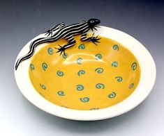 a yellow bowl with a black and white lizard on it