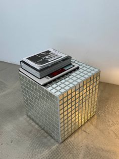 a stack of books sitting on top of a table next to a light that is turned on