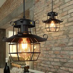 two light fixtures hanging from the ceiling next to a table with wine bottles on it