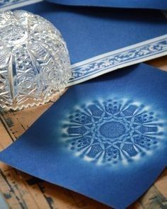 some blue paper with designs on it and a glass bell jar next to the papers