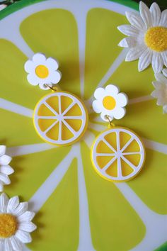 a pair of lemon slices and daisies are on a green plate with white daisies