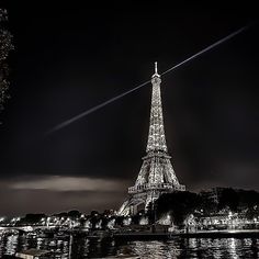 the eiffel tower is lit up at night with lights reflecting in the water