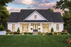 a white house with black shingles and windows in the front yard at night time