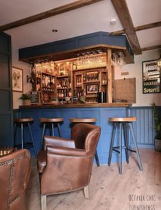 the interior of a bar with brown leather chairs and wooden stools in front of it