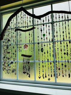 a window with beads hanging from it's side and a tree branch in the middle