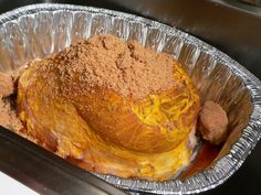 there is a large piece of food in the foil pan on the stove top, with some bread crumbs sticking out of it