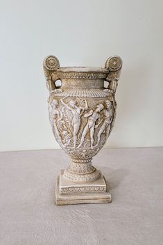 an antique vase is sitting on the floor in front of a white wall and beige carpet