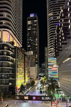 a city street at night with tall buildings in the background