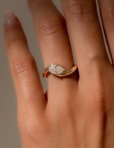 a woman's hand with a gold ring on top of it and a diamond in the middle