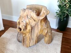 a wooden elephant statue sitting on top of a rug next to a potted plant