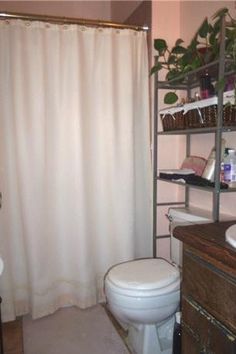 a white toilet sitting next to a bathroom sink under a shower curtain in a bathroom