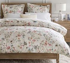 a bed with floral sheets and pillows on it