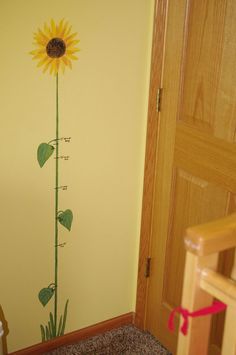 a yellow wall with a sunflower painted on it's side next to a crib