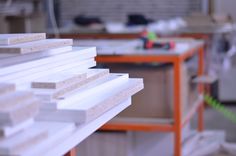 several pieces of white wood sitting on top of a wooden shelf in a room filled with construction equipment