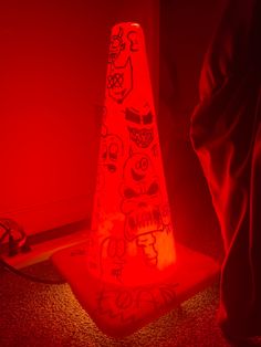 a red light that is on top of a cone with graffiti written on the side