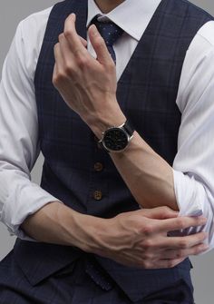 a man in a suit and tie is holding his hands together while wearing a watch