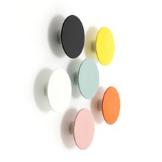 four different colors of knobs on a white wall with one black, one yellow and one pink