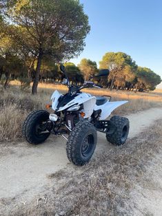 a white four - wheeler parked on the side of a dirt road