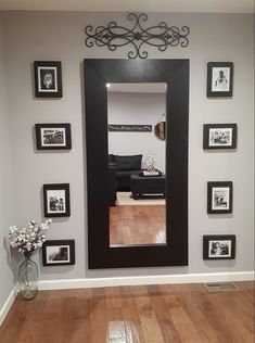 a large black framed mirror sitting on top of a wall next to a wooden floor