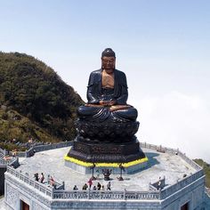 a large buddha statue sitting on top of a stone platform next to a mountain range