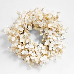 a wreath with white flowers is shown on a white surface and looks like it has been made out of glass