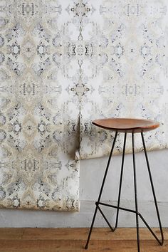 a wooden table sitting in front of a wall with an ornate pattern on the wall