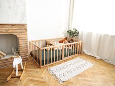 a baby crib in the corner of a room next to a fire place and rug